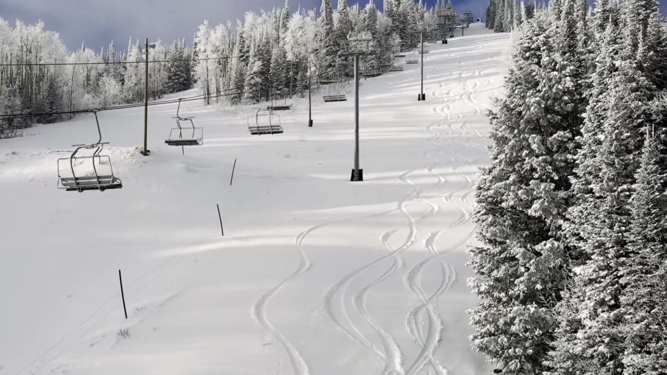 Snow-covered ski slope featuring multiple chairlifts and snow-laden evergreen trees