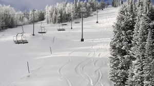 Snow-covered ski slope featuring multiple chairlifts and snow-laden evergreen trees