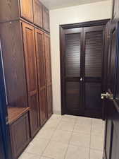 Foyer with light tile patterned flooring and baseboards