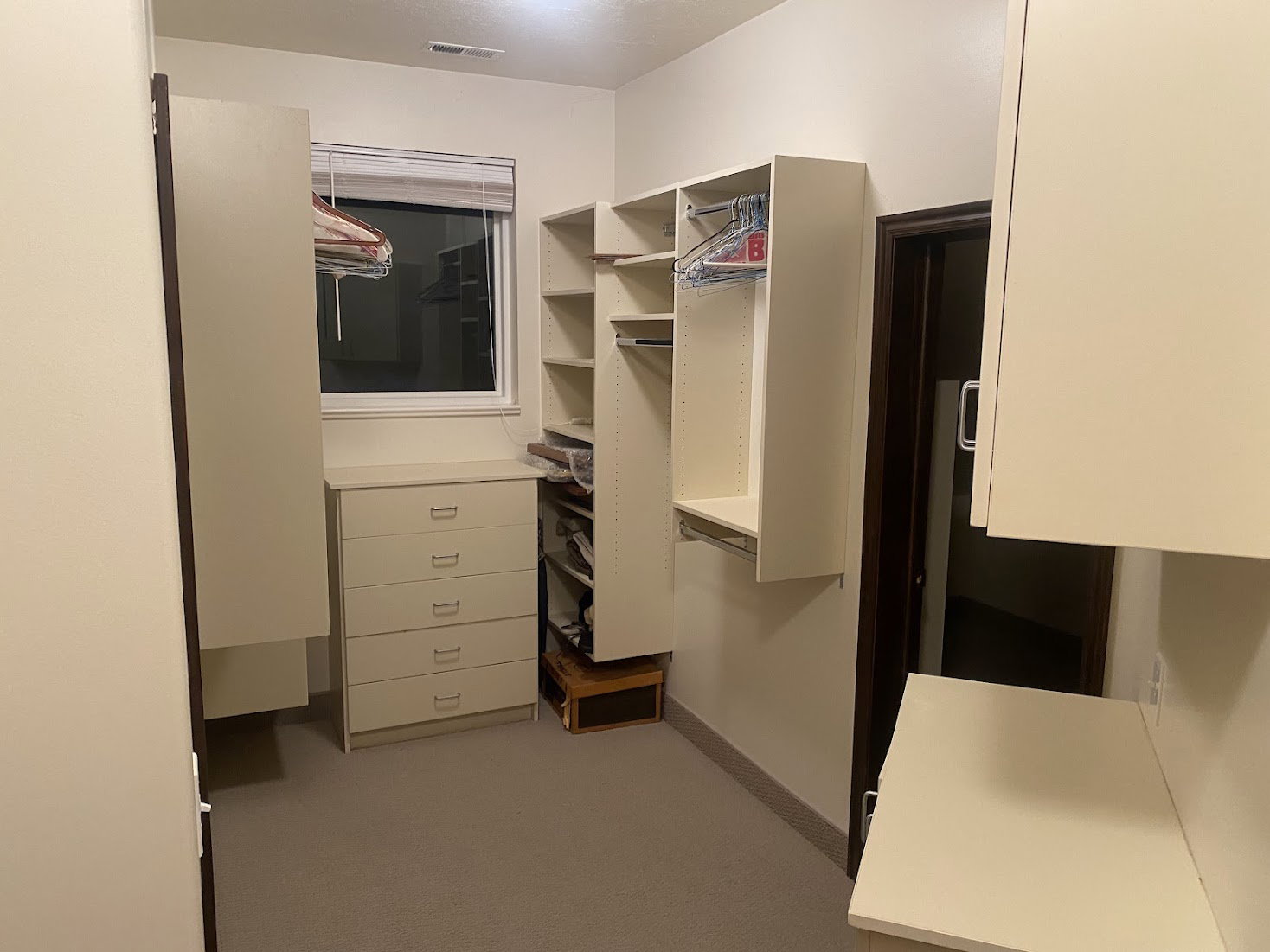 Walk-in closet featuring extensive built-in shelving, hanging rods, and a five-drawer dresser