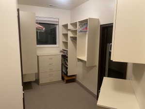 Walk-in closet featuring extensive built-in shelving, hanging rods, and a five-drawer dresser