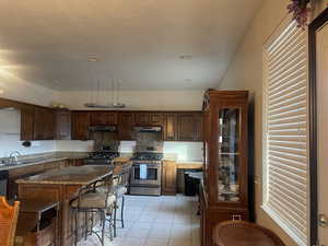 Kitchen with sink, appliances with stainless steel finishes, a kitchen island, dark stone counters, and backsplash