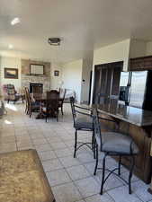 Dining area with a textured ceiling, light tile patterned floors, and a fireplace