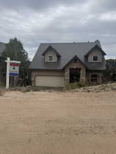 Two-story residence featuring a metal roof, dormer windows, and a stone facade accent