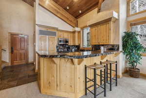 Kitchen featuring a kitchen bar, kitchen peninsula, high vaulted ceiling, and decorative backsplash