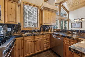 Kitchen featuring stainless steel appliances, sink, backsplash, and decorative light fixtures