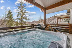 Snow covered pool with a grill, a hot tub, and a mountain view