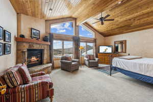 Bedroom with a fireplace, carpet flooring, high vaulted ceiling, and wooden ceiling