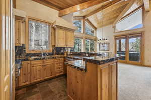 Kitchen featuring beamed ceiling, sink, wooden ceiling, and decorative light fixtures