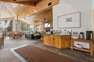 Kitchen featuring high vaulted ceiling, a fireplace, dark carpet, wood ceiling, and beam ceiling