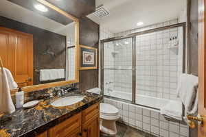 Full bathroom featuring vanity, toilet, and combined bath / shower with glass door