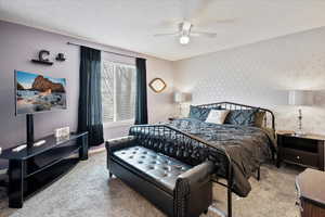 Carpeted bedroom featuring ceiling fan and a textured ceiling