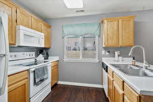 Kitchen featuring white appliances, dark hardwood / wood-style floors, and sink