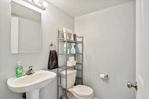 Bathroom featuring sink, a textured ceiling, and toilet