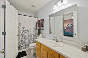 Bathroom with vanity, ceiling fan, toilet, and a shower with shower curtain