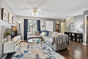 Living room featuring ceiling fan, dark hardwood / wood-style floors, and a textured ceiling