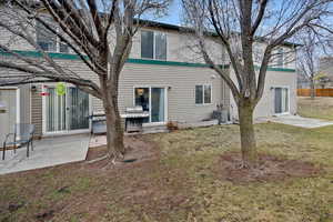 Back of house featuring central AC, a patio area, and a lawn