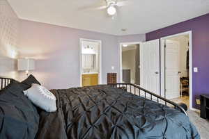 Carpeted bedroom featuring ceiling fan, ensuite bath, and sink