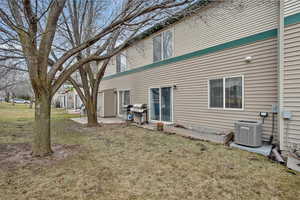 Rear view of property featuring cooling unit and a lawn