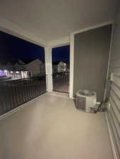 Patio at twilight featuring a balcony and cooling unit