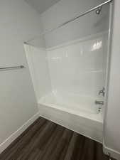 Bathroom with hardwood / wood-style flooring and washtub / shower combination