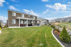 Rear view of house featuring a pergola, a patio area, a mountain view, a lawn, and stucco siding