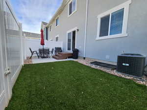 Rear view of house featuring a yard, central AC unit, and a patio area