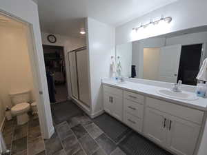 Bathroom featuring vanity, a shower with door, and toilet