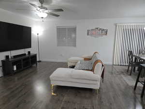 Living room with ceiling fan and dark hardwood / wood-style flooring