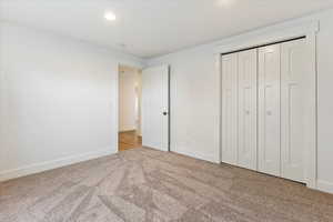 Unfurnished bedroom with light colored carpet and a closet