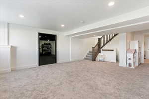 Basement featuring light carpet and a textured ceiling