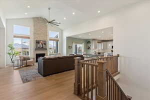 Living room featuring a healthy amount of sunlight, a fireplace, high vaulted ceiling, and light wood-type flooring