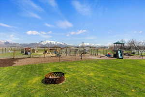 View of jungle gym featuring a mountain view, a yard, and a fire pit