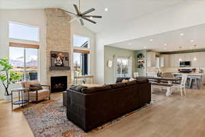 Living room featuring high vaulted ceiling, light hardwood / wood-style flooring, a mountain view, ceiling fan, and a fireplace