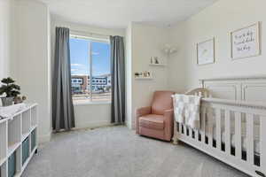 Bedroom featuring light carpet and a nursery area