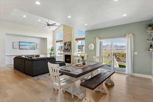 Dining area featuring a fireplace, lofted ceiling, light hardwood / wood-style floors, a mountain view, and a textured ceiling