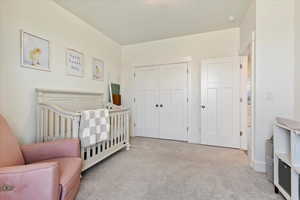 Bedroom featuring light carpet and a closet