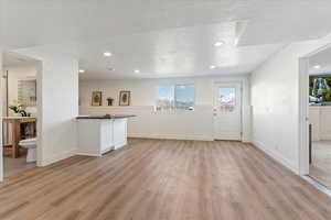 Unfurnished living room featuring a textured ceiling and light hardwood / wood-style flooring