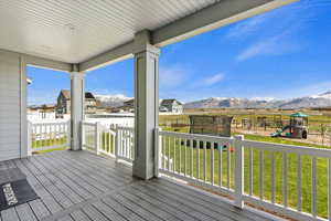 Wooden deck featuring a playground, a mountain view, a trampoline, and a lawn