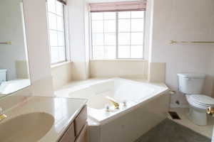 Bathroom with vanity, a tub, and toilet