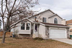 View of front of house with a garage, a front yard, and central AC unit