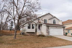 View of front of house featuring a garage, central AC unit, and a front lawn