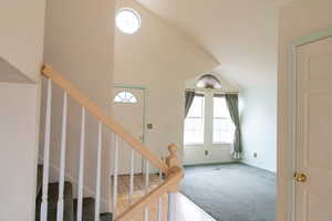 Staircase with carpet floors and high vaulted ceiling