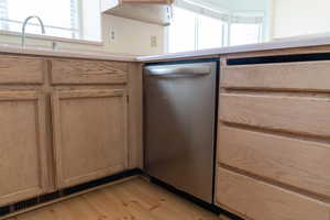 Kitchen with light brown cabinetry, dishwasher, and light hardwood / wood-style floors