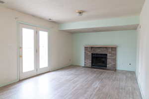 Unfurnished living room with a brick fireplace and light wood-type flooring