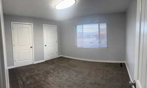 Unfurnished bedroom with dark carpet