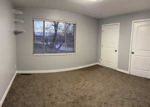 Unfurnished bedroom with dark carpet and a textured ceiling