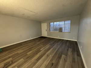 Unfurnished room with dark wood-type flooring and a textured ceiling