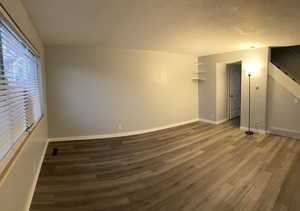 Unfurnished room with dark wood-type flooring and a textured ceiling