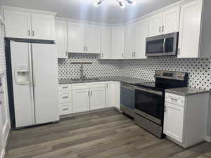 Kitchen featuring white cabinetry, sink, stainless steel appliances, and dark hardwood / wood-style floors